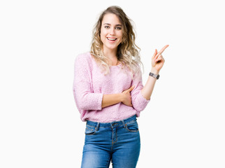 Beautiful young blonde woman over isolated background with a big smile on face, pointing with hand and finger to the side looking at the camera.