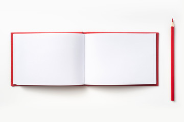 Top view of red hardcover notebook and pencil