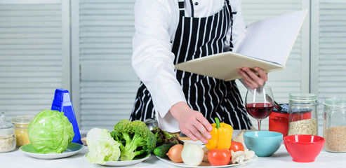 Culinary arts concept. Improve cooking skill. Ultimate cooking guide for beginners. Book family recipes. According to recipe. Man bearded chef cooking food. Guy read book recipes. Man learn recipe