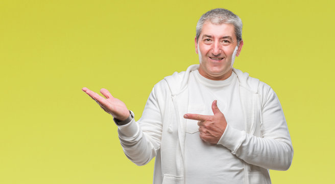 Handsome senior man wearing sport clothes over isolated background amazed and smiling to the camera while presenting with hand and pointing with finger.