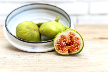 Ripe halved figs on old wood table with antique white enamel bucket
