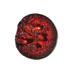Single aronia (chokeberry) fruit cut in half, red pulp and seeds visible, isolated on white background.