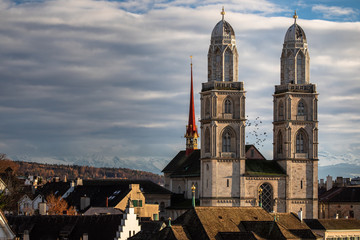 Obraz premium Zurich, Switzerland - view of the Grossmunster church with beautiful mountains in the background