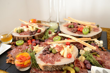 assorted cheeses, jamon and sausages with pickles and olives, on wooden boards