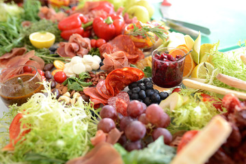 assorted cheeses, jamon and sausages with pickles and olives, on wooden boards