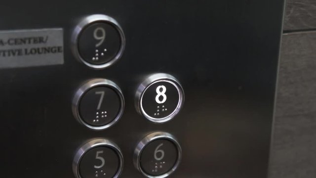 Female hand presses the button in the elevator