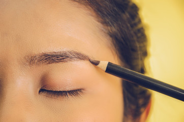 Beauty face of Asian woman by applying eyebrow pencil and smooth skin by cosmetics.