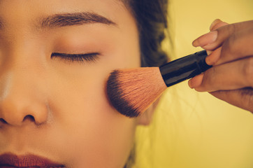 Beauty face of Asian woman by applying brushes and smooth face skin by cosmetics.
