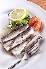 SARDINAS CON LIMÓN LECHUGA TOMATE SOBRE PLATO BLANCO