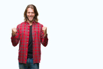 Young handsome man with long hair over isolated background very happy and excited doing winner gesture with arms raised, smiling and screaming for success. Celebration concept.