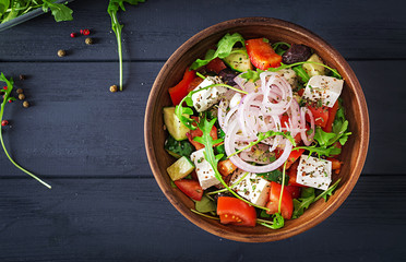 Greek salad with fresh tomato, cucumber, red onion, basil, feta cheese, black olives and Italian herbs. Top view