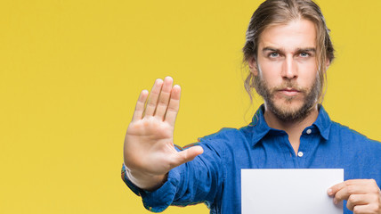 Young handsome man with long hair over isolated background holding blank paper with open hand doing...