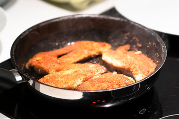 Schnitzel cooking in a pan.