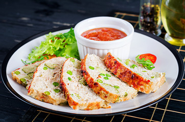 Tasty homemade ground  baked chicken meatloaf with green peas and broccoli on black table. Food american meat loaf.