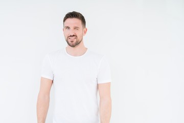 Young handsome man wearing casual white t-shirt over isolated background winking looking at the...