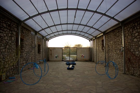 Abandoned and closed playground and toys at the stone yard of warehouses under a roof of a glass and plastic dome in the afternoon at Koprena village in the shore of Ambracian gulf