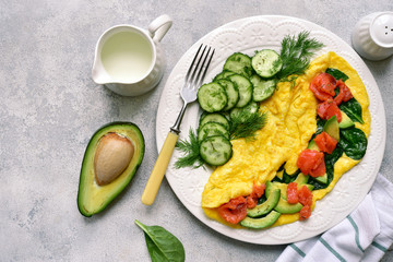 Omelette stuffed with spinach, cheese, avocado and salted salmon.Top view with copy space.