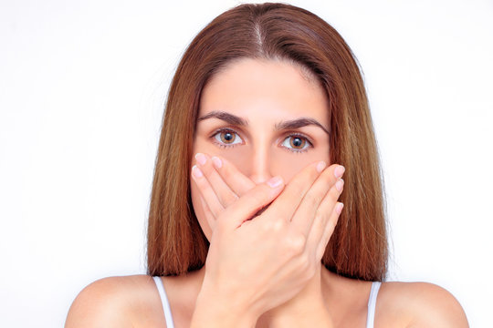 Beautiful woman closes her mouth with her hands