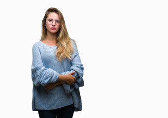 Young beautiful blonde woman wearing sweater and glasses over isolated background with serious expression on face. Simple and natural looking at the camera.