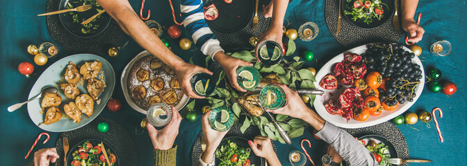 Company of friends gathering for Christmas or New Year party dinner at festive table. Flat-lay of...