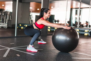 Cheerful adult woman training with medicine ball