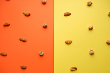 Hazelnut and almond pattern on a yellow-orange background, top view
