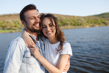 Fototapeta premium Cheerful couple hugging near lake