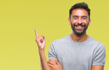 Adult hispanic man over isolated background with a big smile on face, pointing with hand and finger to the side looking at the camera.