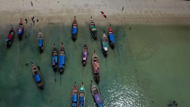 Aerial view of the long tail boats, kayaks and people walking on the sand at Loh Dalum beach in Koh Phi Phi, Thailand. Drone 4K footage close up on a sunny day of a summer.