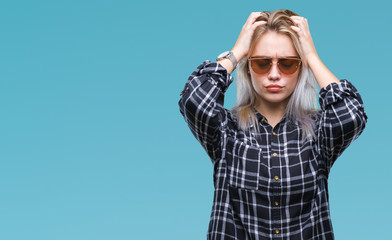 Young blonde woman wearing sunglasses over isolated background suffering from headache desperate and stressed because pain and migraine. Hands on head.