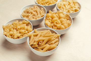 Different pasta types in bowls on the table.