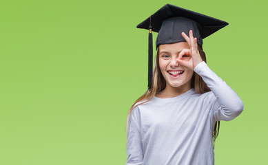 Young beautiful girl wearing graduate cap over isolated background doing ok gesture with hand smiling, eye looking through fingers with happy face.