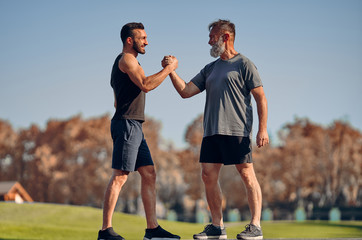 The young and old athletes greeting in the beautiful park