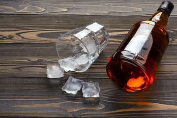 bottle and glass of whiskey on a wooden background