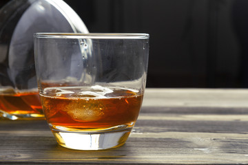 whiskey with ice cubes on wooden background