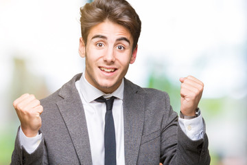 Young business man wearing suit and tie over isolated background celebrating surprised and amazed for success with arms raised and open eyes. Winner concept.