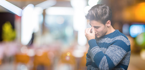 Young handsome man over isolated background tired rubbing nose and eyes feeling fatigue and headache. Stress and frustration concept.