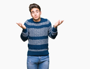 Young handsome man over isolated background clueless and confused expression with arms and hands...