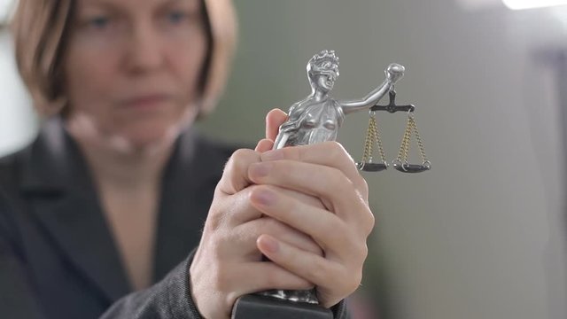 State attorney holding statue of Justice in office, selective focus