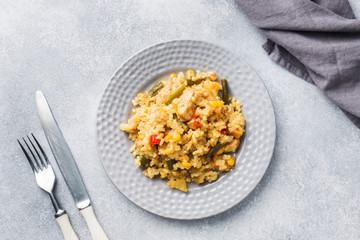 Pilaf with vegetables and chicken in a gray plate on a gray background.