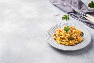 Pilaf with vegetables and chicken in a gray plate on a gray background. Copy space