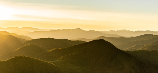 Panoramic view of sunrise over the mountain peak with sun ray to the yellow mountain range. Landscape Background