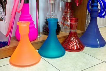 Bright beautiful glass hookahs on the shop window. Hookah pipes, mouthpieces,  flasks. Choosing a gift. colorful background