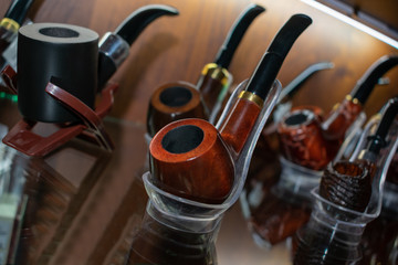 Obraz na płótnie Canvas Different Smoking pipes in the shop window. Choose gifts for the holiday. Beautiful men's accessories. Smoke.