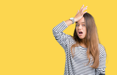 Young beautiful brunette woman wearing stripes sweater over isolated background surprised with hand...