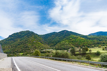 Mountain road at sunset. Landscape with rocks, orange sunny sky with clouds and beautiful asphalt road in the evening in summer. Vintage toning. Travel background. Scenery with highway. Transportation