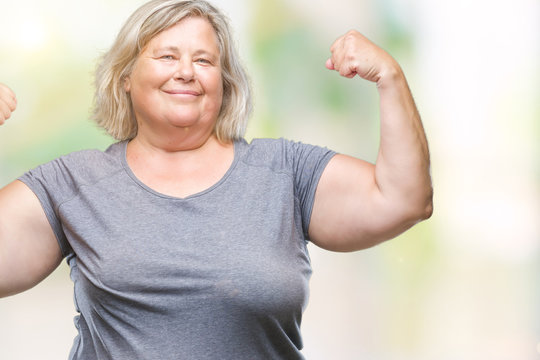 Senior plus size caucasian woman over isolated background showing arms muscles smiling proud. Fitness concept.