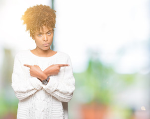 Beautiful young african american woman wearing winter sweater over isolated background Pointing to both sides with fingers, different direction disagree