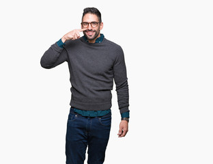 Young handsome man wearing glasses over isolated background Pointing with hand finger to face and nose, smiling cheerful