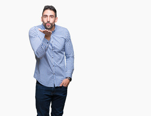 Young handsome man over isolated background looking at the camera blowing a kiss with hand on air being lovely and sexy. Love expression.